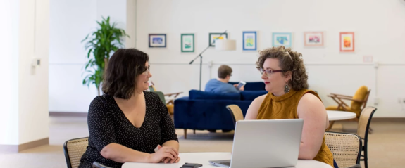 Two people talking in front of a laptop